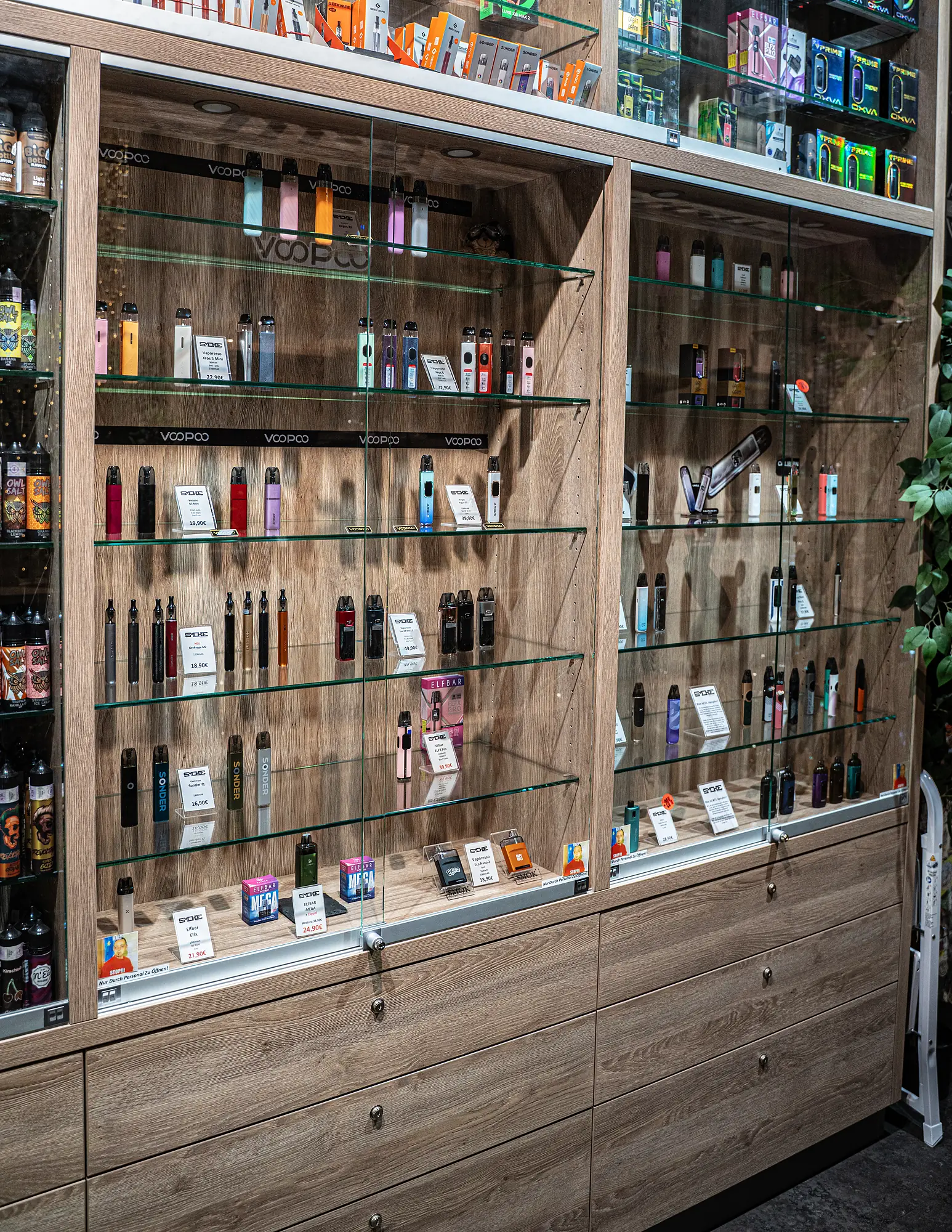 Pod-Systeme und E-Zigaretten auf Glasböden mit Preisschildern bei SmokeFactory Köln am Neumarkt