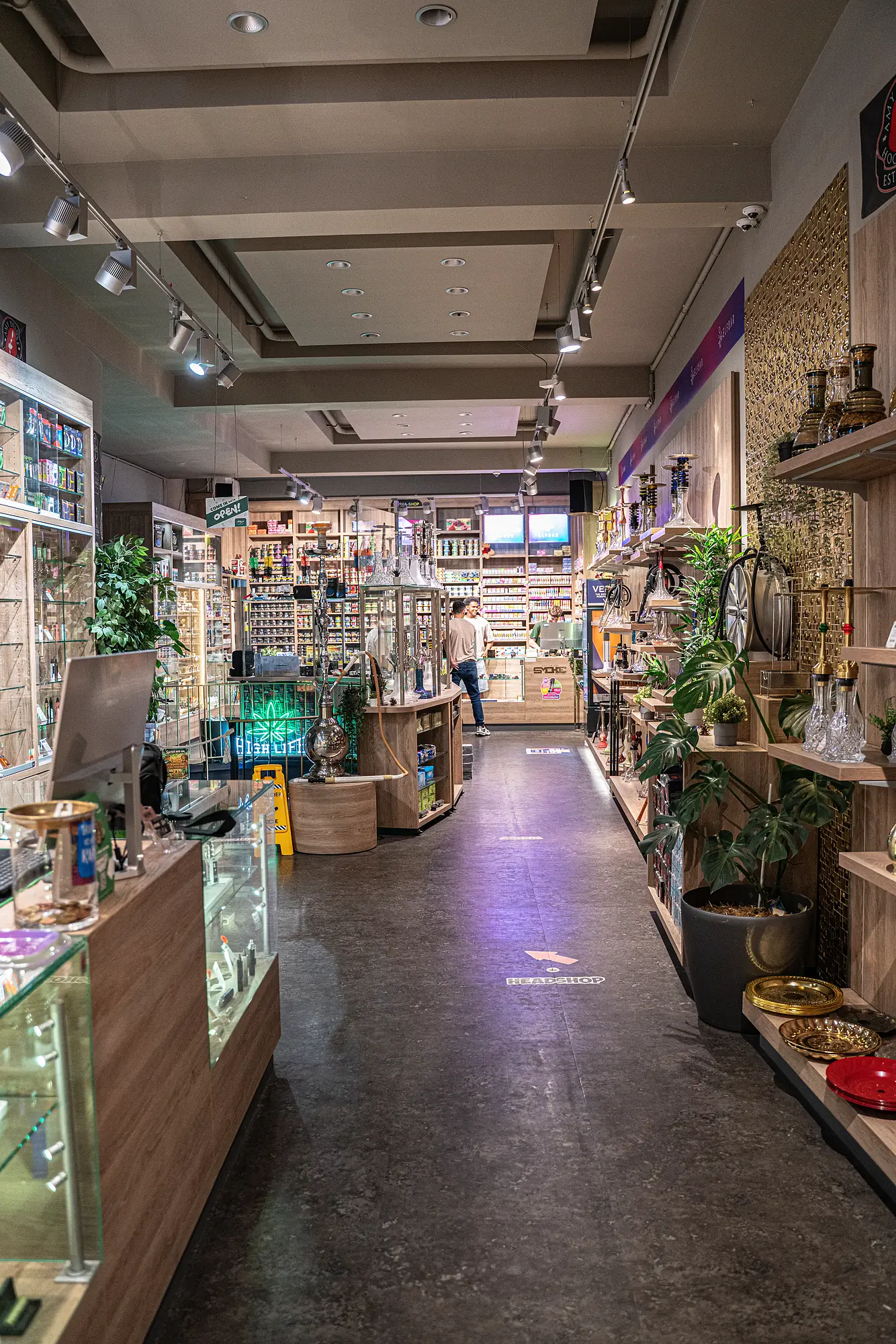 Blick in den SmokeFactory-Laden am Kölner Neumarkt — Gang zwischen Shisha-Regalen und Vitrinen