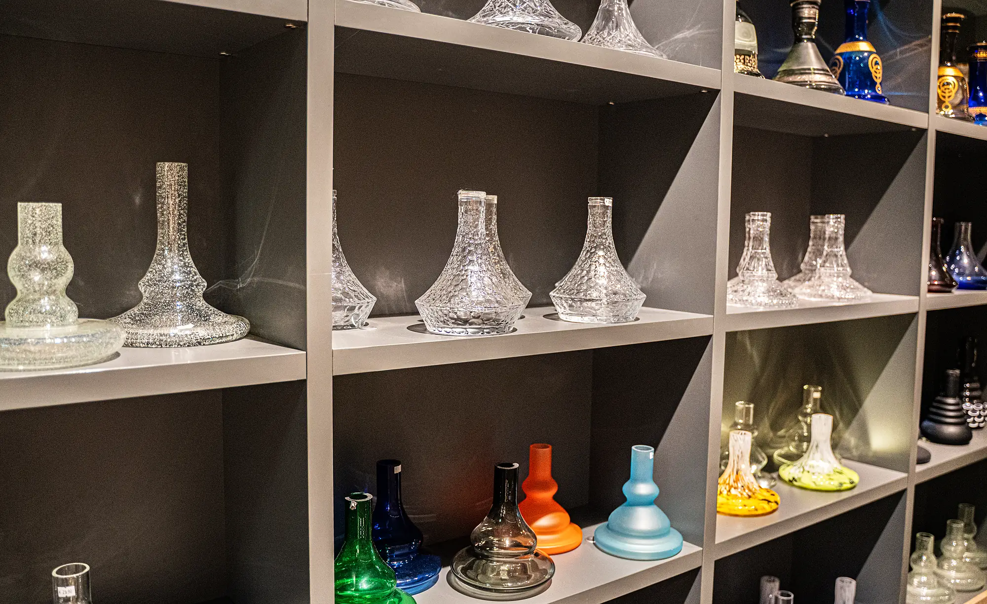 Glas-Shisha-Basen in verschiedenen Farben im Regal bei SmokeFactory Köln